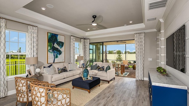 living room featuring hardwood / wood-style flooring, ceiling fan, and a tray ceiling