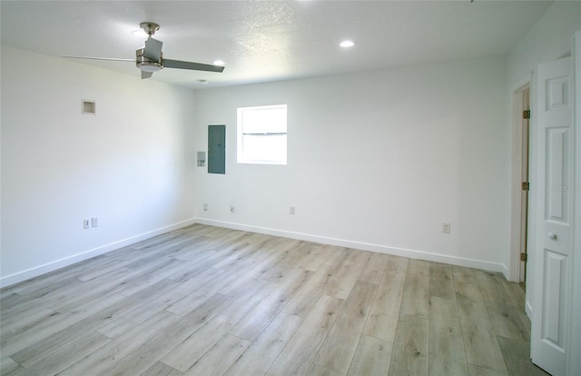 empty room with ceiling fan, electric panel, and light hardwood / wood-style flooring