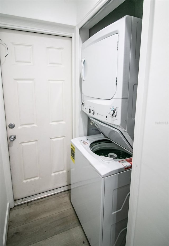 laundry room featuring stacked washer / dryer and dark hardwood / wood-style flooring