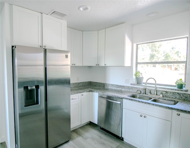 kitchen with white cabinetry, appliances with stainless steel finishes, sink, and a textured ceiling