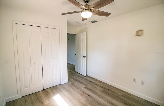 unfurnished bedroom with ceiling fan, light wood-type flooring, and a closet