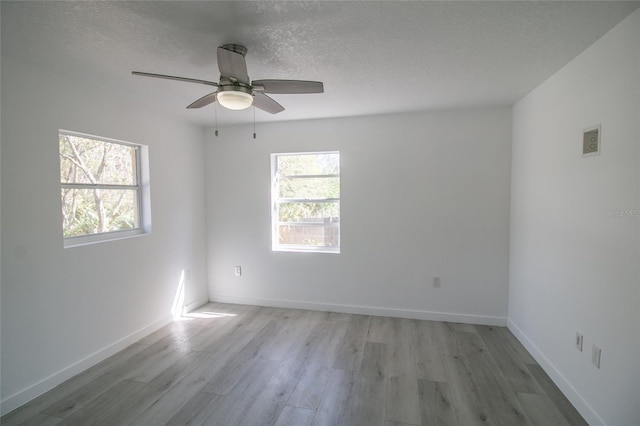 empty room with ceiling fan, a textured ceiling, and light hardwood / wood-style flooring