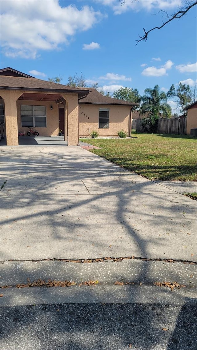 view of front of property with a front yard, fence, driveway, and stucco siding