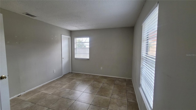 empty room featuring light tile patterned floors and a textured ceiling