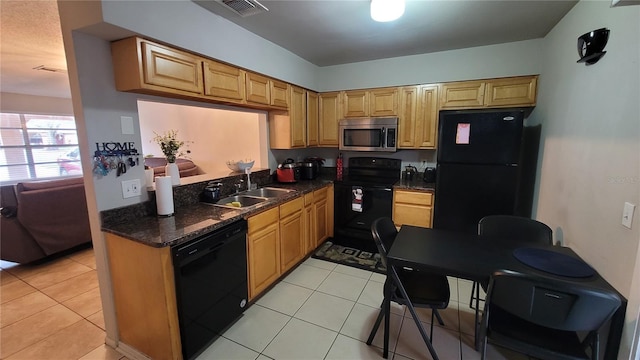 kitchen featuring dark stone countertops, sink, light tile patterned floors, and black appliances