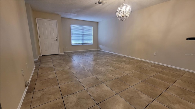 unfurnished room featuring baseboards, visible vents, and an inviting chandelier