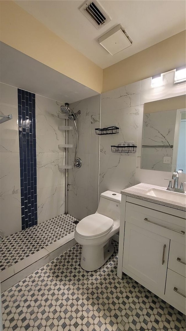 full bath with visible vents, vanity, a tile shower, and toilet