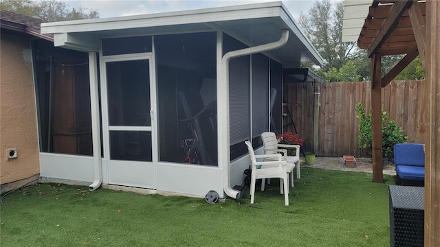 view of side of home featuring a sunroom, stucco siding, fence, and a lawn