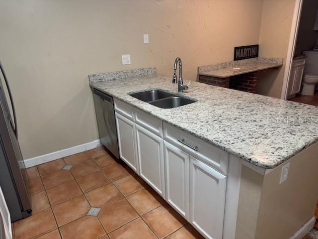 kitchen featuring appliances with stainless steel finishes, sink, white cabinets, kitchen peninsula, and light stone countertops