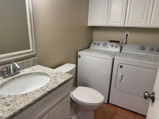 bathroom with tile patterned flooring, vanity, washer and dryer, and toilet