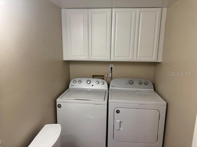 clothes washing area featuring cabinets and separate washer and dryer