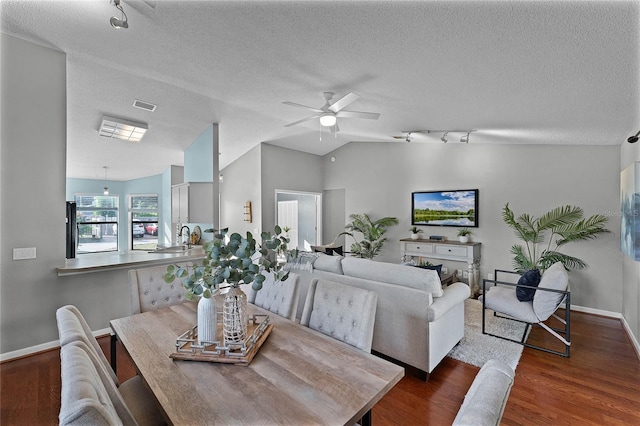 dining space featuring dark wood-type flooring, sink, vaulted ceiling, a textured ceiling, and ceiling fan