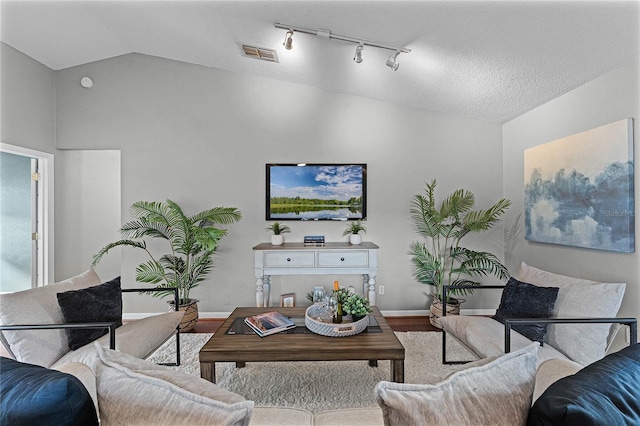 living room with hardwood / wood-style floors, vaulted ceiling, rail lighting, and a textured ceiling