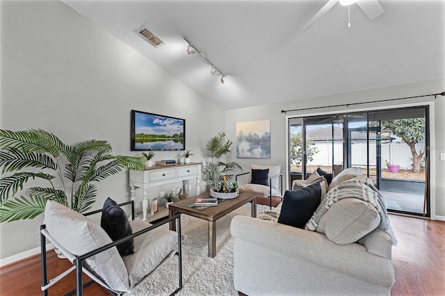 living room featuring lofted ceiling, wood-type flooring, and rail lighting