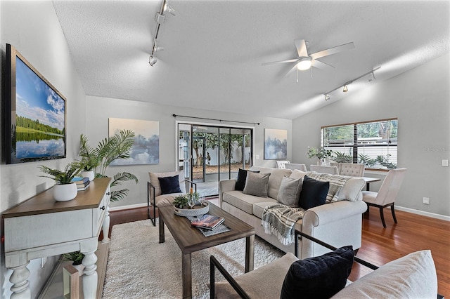 living room with lofted ceiling, a textured ceiling, light hardwood / wood-style floors, and a healthy amount of sunlight