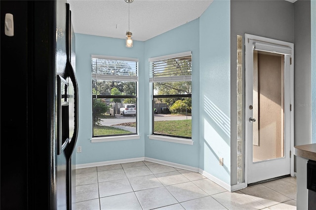 doorway with light tile patterned flooring and a textured ceiling