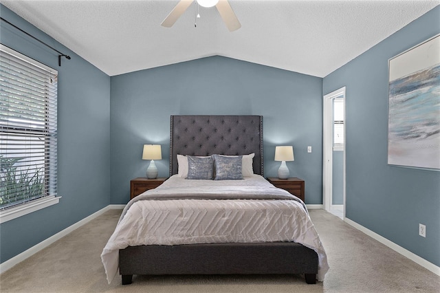 carpeted bedroom with ceiling fan, vaulted ceiling, multiple windows, and a textured ceiling