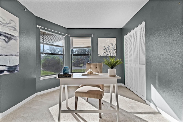 carpeted home office featuring a textured ceiling