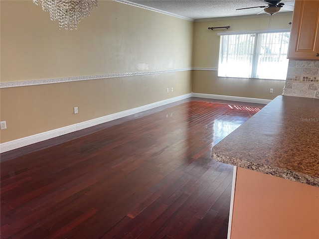 unfurnished dining area featuring dark hardwood / wood-style flooring, ceiling fan, crown molding, and a textured ceiling