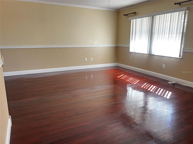 spare room with ornamental molding and dark hardwood / wood-style flooring