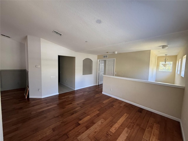 unfurnished room with dark hardwood / wood-style flooring, vaulted ceiling, and a textured ceiling