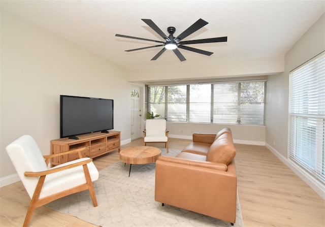 living room featuring ceiling fan, light hardwood / wood-style flooring, and a textured ceiling