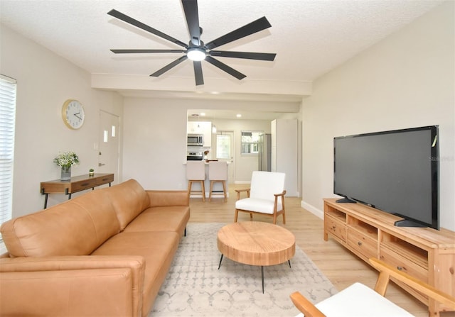 living room with ceiling fan, light hardwood / wood-style floors, and a textured ceiling