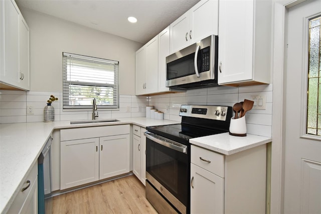 kitchen featuring sink, white cabinetry, stainless steel appliances, light stone counters, and decorative backsplash