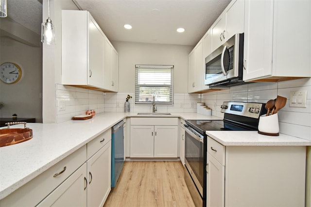 kitchen featuring appliances with stainless steel finishes, white cabinetry, sink, hanging light fixtures, and light stone counters