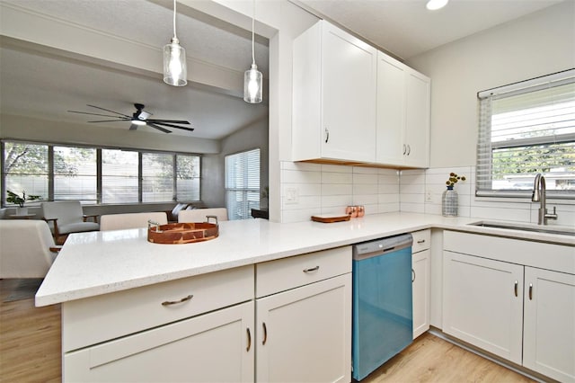 kitchen featuring pendant lighting, sink, white cabinets, stainless steel dishwasher, and kitchen peninsula