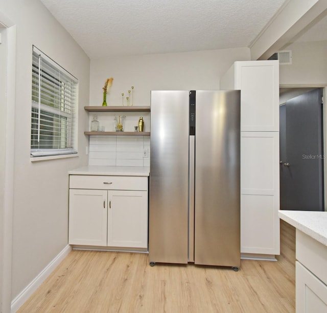 kitchen with white cabinetry, stainless steel fridge, and light hardwood / wood-style flooring