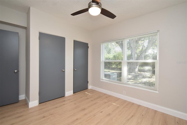 unfurnished bedroom with ceiling fan, light hardwood / wood-style flooring, and a textured ceiling