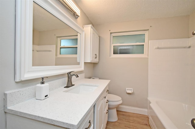 bathroom featuring vanity, wood-type flooring, toilet, and a textured ceiling