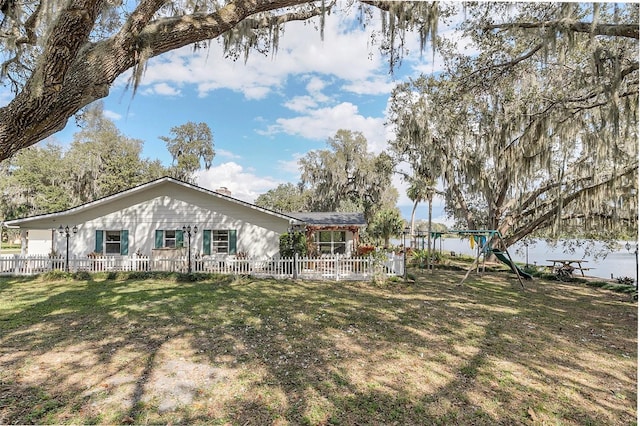 rear view of house with a yard, a playground, and a water view