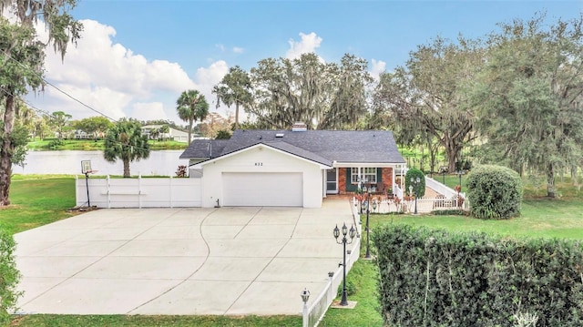 view of front facade with a garage, a front lawn, and a water view