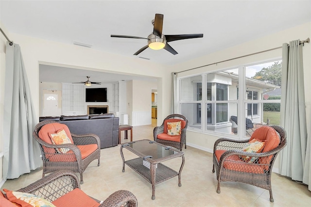 sunroom with a brick fireplace and ceiling fan