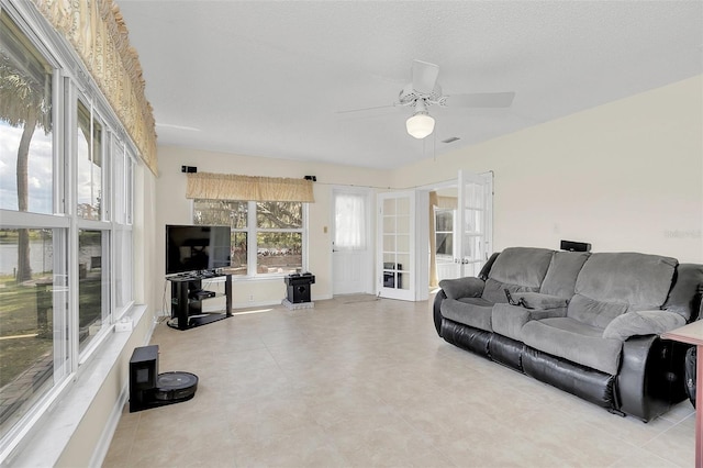 living room with french doors, ceiling fan, and a textured ceiling