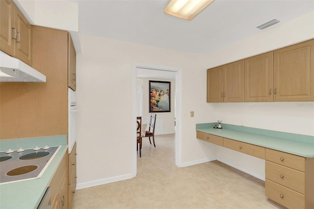 kitchen featuring cooktop, built in desk, and oven