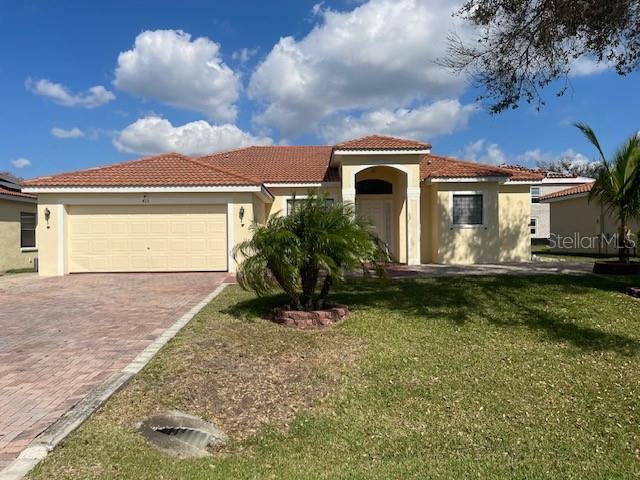 mediterranean / spanish house with a garage and a front lawn