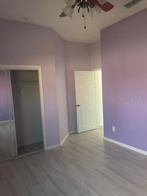 unfurnished bedroom with vaulted ceiling, ceiling fan, light hardwood / wood-style floors, and a closet