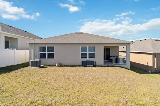 back of property with central AC and a lawn