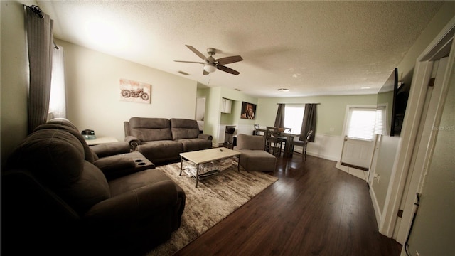 living room with ceiling fan, dark hardwood / wood-style floors, and a textured ceiling