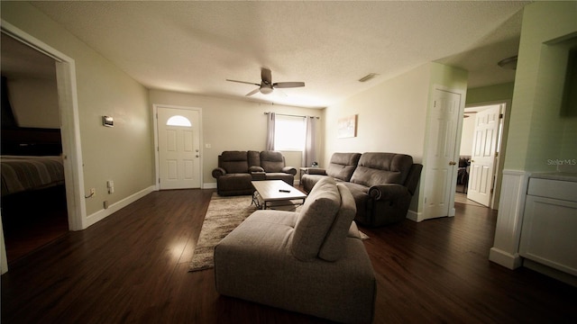 living room featuring dark hardwood / wood-style flooring, ceiling fan, and a textured ceiling