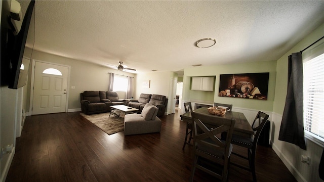 living area featuring dark wood-style flooring, a textured ceiling, and baseboards