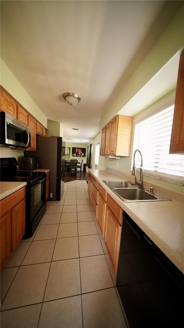 kitchen with black appliances, plenty of natural light, a sink, and light tile patterned flooring