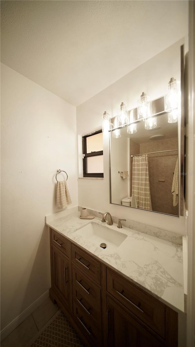 full bath with curtained shower, tile patterned flooring, vanity, and baseboards