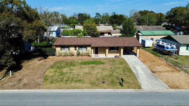 ranch-style home with a porch, a front yard, fence, a carport, and driveway