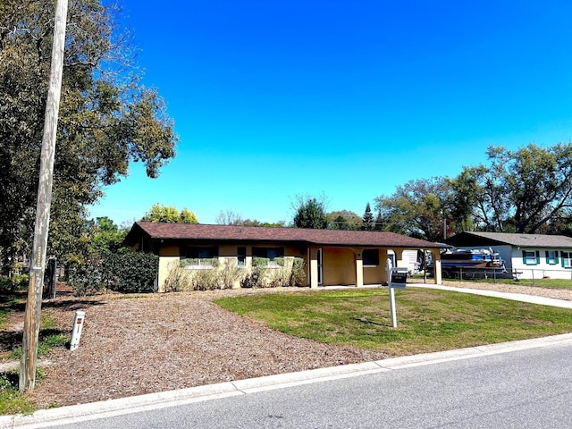 ranch-style house featuring a carport, driveway, and a front lawn