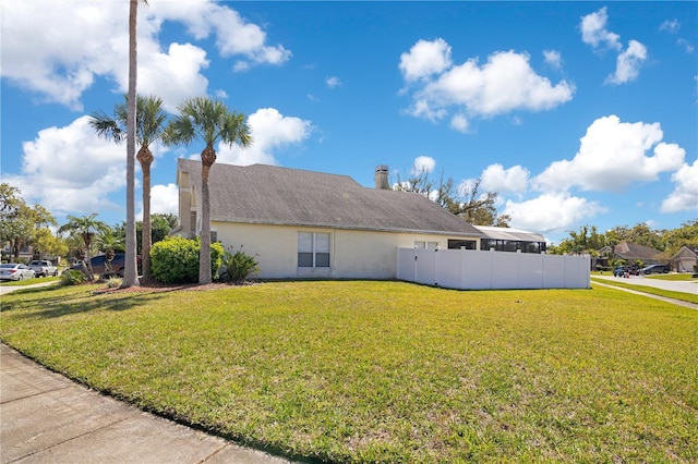 exterior space featuring fence, a lawn, and stucco siding