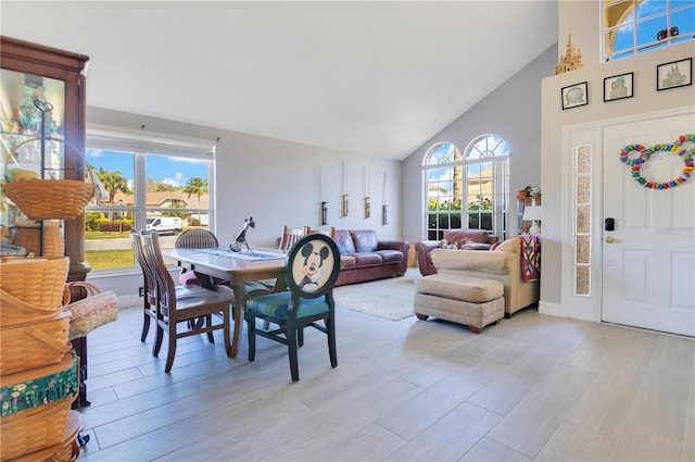 dining room with light wood-style floors and high vaulted ceiling